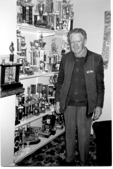 Tom standing by all his winning trophies