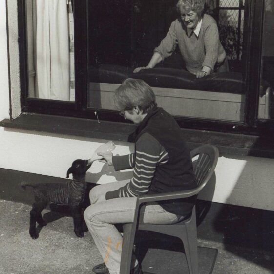 Doreen Hynes & her late mother Chrissie Mulryan Doreen Hynes feeding a pet lamb at her home in Creevaghbaun, watched by her mother Chrissie inside the window | Photo: Doreen Hynes given to Mary Ellen Burke for Out and About magazine