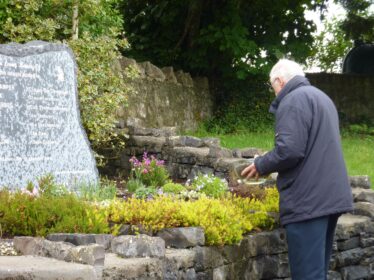 Sylvester Cassidy sprinkling some clay that had been gathered from each unmarked children's burial ground in the oarish, at the base of the new memorial stone. | B. Connolly