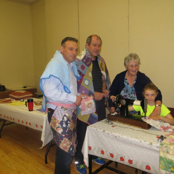 Brendan and Seamus modelling crochet work watching Sarah Ahern, Togher, completing her patchwork project watched by her teacher Eileen Reynolds, Cloonlusk | Photo: Bernadette Forde