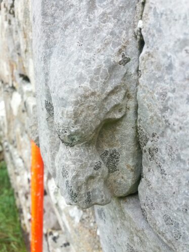 Late medieval carved head with flowing hair on the archway of church door
