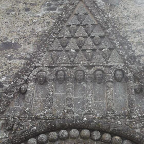 Detail showing the pediment with carved heads within triangular relief pattern. Clonfert Cathedral doorway. Each head is different in design with its own character | B. Doherty 2017