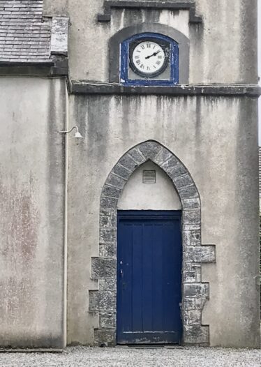 Blue rectangular door within and older stone arched door opening.