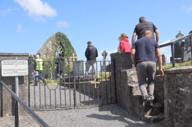 People walking up steps at the entrance to Cloonkeenkerrill graveyard