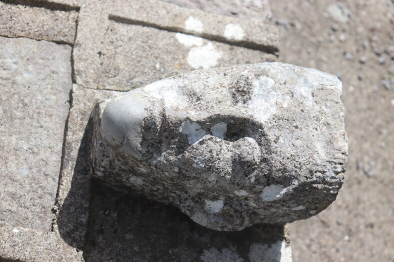 Head carving was once a corbel and now re-used on St. Kerrills 'bed' just inside the graveyard wall at the graveyard. | B. Doherty
