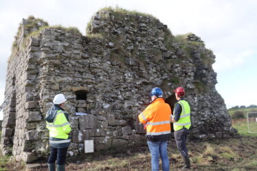 drystone wall in background, three people in hi visibility clothes and hard hads discussing proposed works