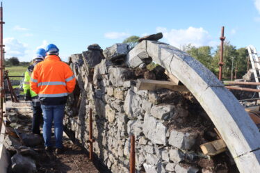 Detail showing apex of stone arch, engineer walking and inspecting on scaffold. | B. Doherty