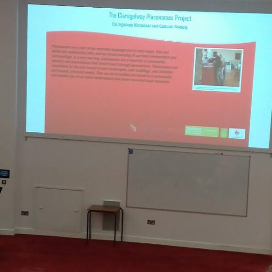 Archaeologist highlighting importance of placenemaes. Big screen behind speaker at conferenceg | B. Doherty