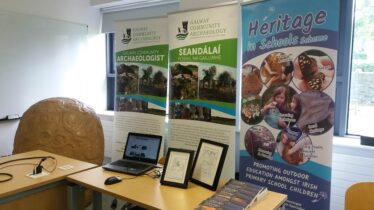 Pull up banners behind a table with books, laptop and turoe replica to the side.