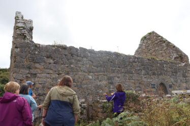 Community listen intently during tour of Mainistir Chiaráin by Sinéad | B. Doherty 2022