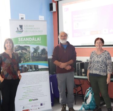 Three archaeologists posing in fromt of screen and banner for Galway Comunity Archaeology Projecr | Jo Moran