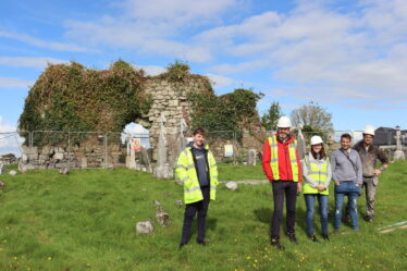 Four people standing in front of ruinous church