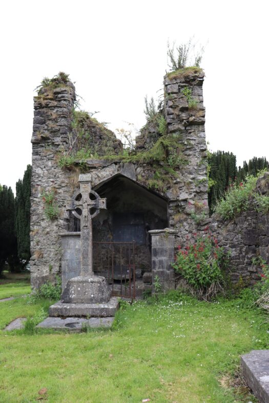 Celtic cross memorial in front of stone structure with an opening | B. Doherty 2023