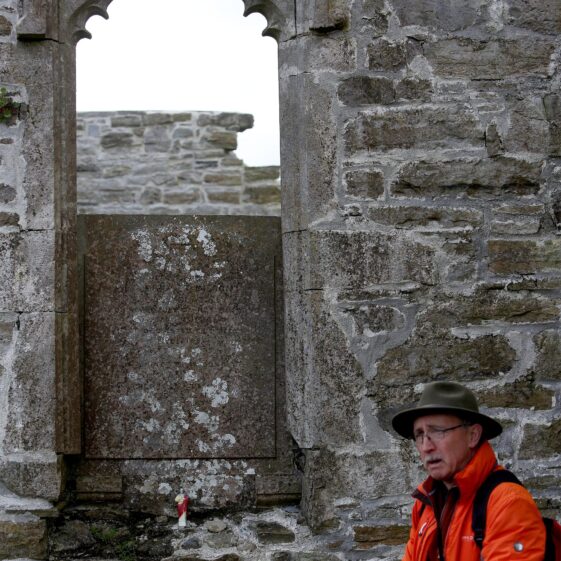 MAn in a hat talking about the inscribed wall plate on a stone wall | Hany Marzouk