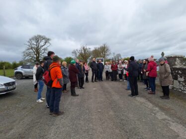 People stand in the carpark outside the gate at Abbeygormican and listen to how works came about