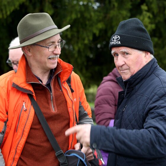 Man in orange coat and hat smiles with another man in blue fleece and black hat | Hany Marzouk