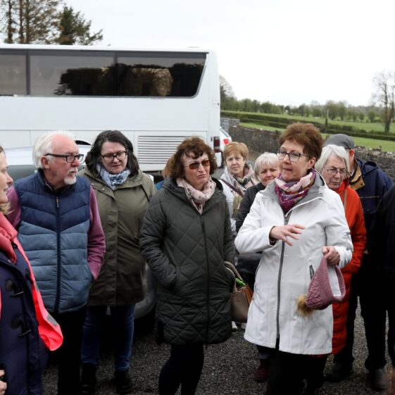 People n fron of a big white bus listens to lady talking | Hany Marzouk