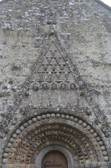 Upper-gable- of romanesque doorway at Clonfert showing detailed carved human-heads-within-triangular-frames
