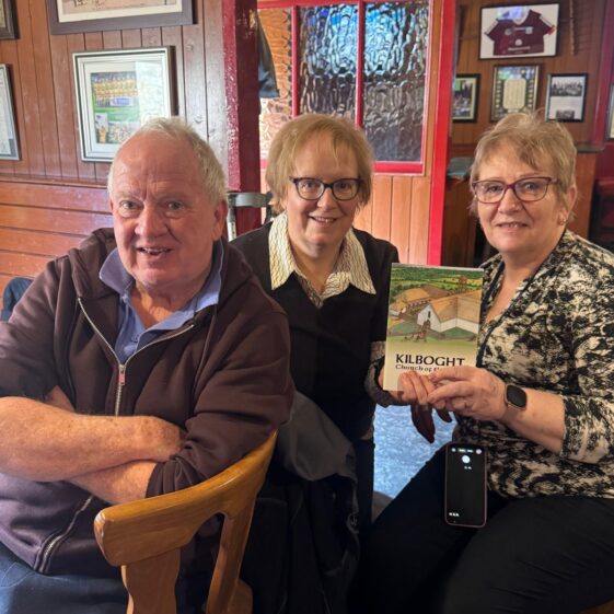Two women and a man posing for a picture with a book at. | Lucy Flynn 2026
