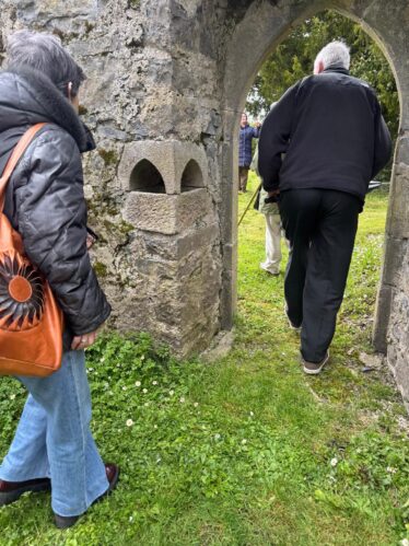 A picture of people walking through the doorway in Kilboght as they pass by the font built into the wall. | Lucy Flynn 2026