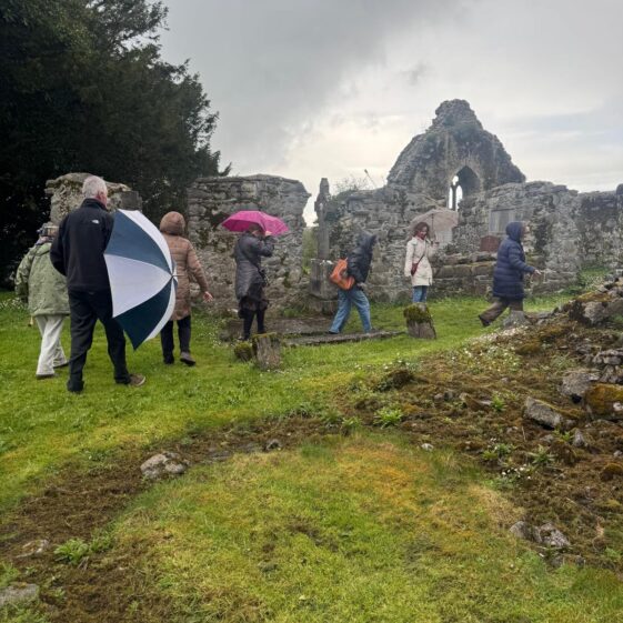 A line of people walking through the ruins of Kilboght friary. | Lucy Flynn 2026