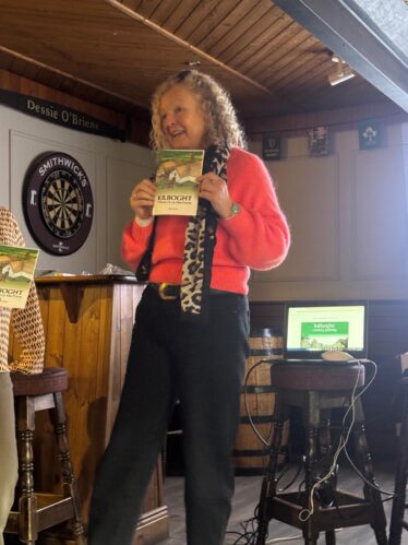 A lady smiling and proudly holding up a book.