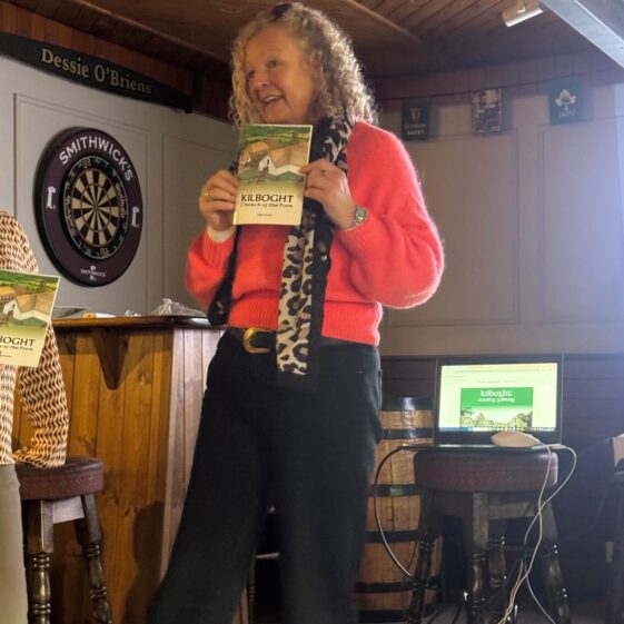 A lady smiling and proudly holding up a book. | Lucy Flynn 2026