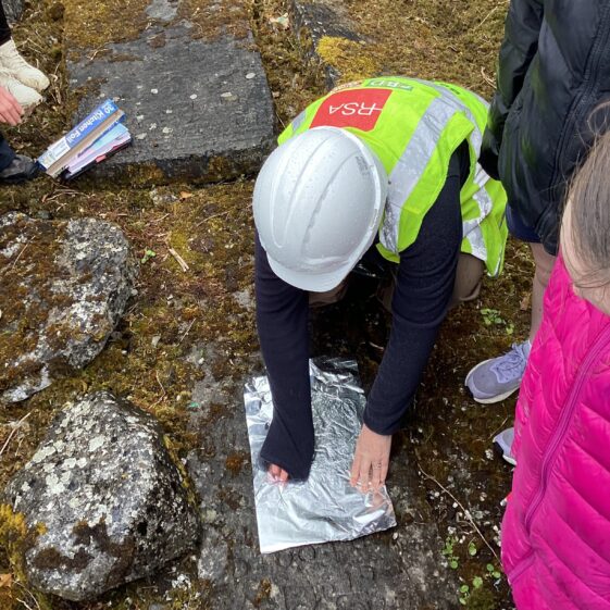 Person in hard hat rubbing memoral with tin-foil to see occupation of deceased | Carmel O'Riordan
