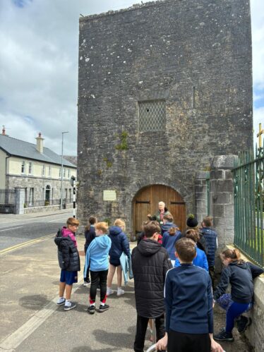Stone building with wooden arched door was the town gate to Loughrea. Group of children looking at the structure | Kenneth Cooney