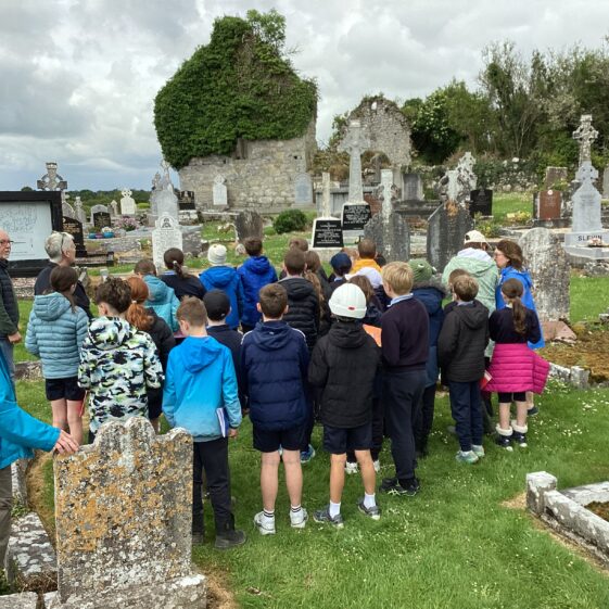Group of children listening to Community Archaeologist talk about remaining structure behind them | Carmel O'Riordan