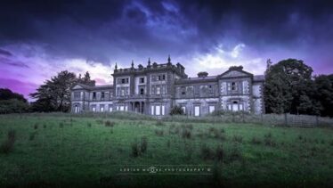 Storm Clouds hover over Woodlawn House with green grass in foreground