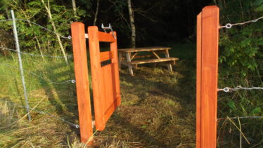 Picnic area near river, Woodlawn, open gate showing wooden bench