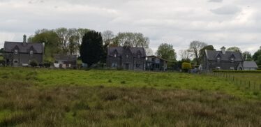 stone houses facing railway with green grass in froeground