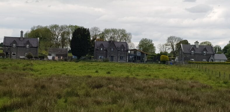 stone houses facing railway with green grass in froeground | Angela Magennis