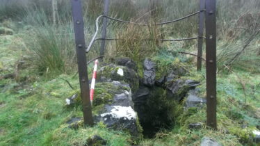 D shaped stone lined well with iron railing