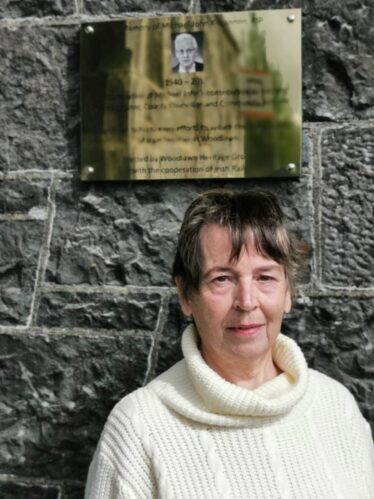 Maureen, Michael Johns wife standing beside the plaque