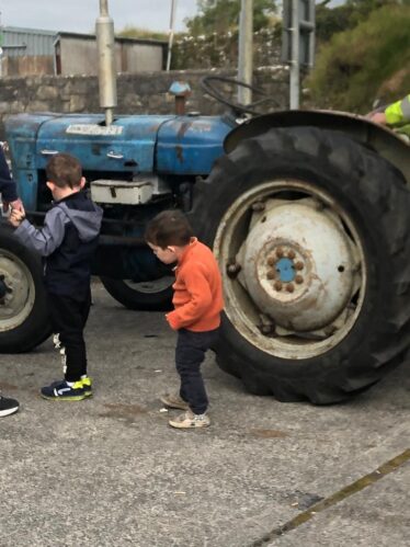 blue tractor with two children looking around it
