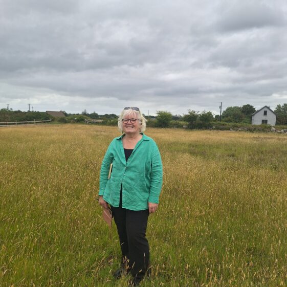 Mary O' Shea standing at the location where Cloch Mór Liagáin is reputed to have stood.