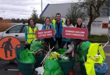 People standing with bags of rubbish in front of them showing signs saying keep galway tidy