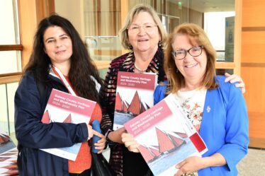 Three ladies smiling, holding the new book
