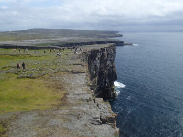 Sea cliffs on the southern edge of Inish Mor on Oileann Arainn.  The cliffs expose beds of limestone and bear testament to the ferocious power of the Atlantic waves.  The ice sculpted, bare limestone pavement of the rest of the island terrain is seen in the distance.
