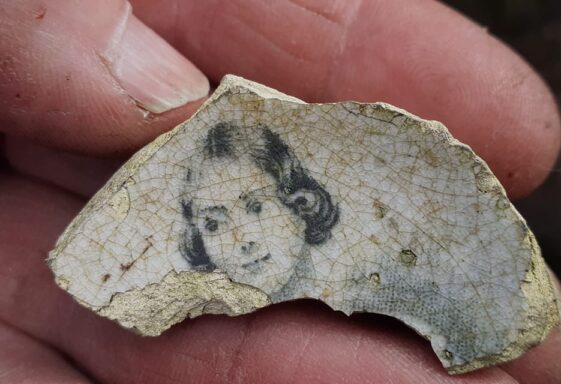 Inside bottom of a broken cup or mug, decorated with a smiling girl